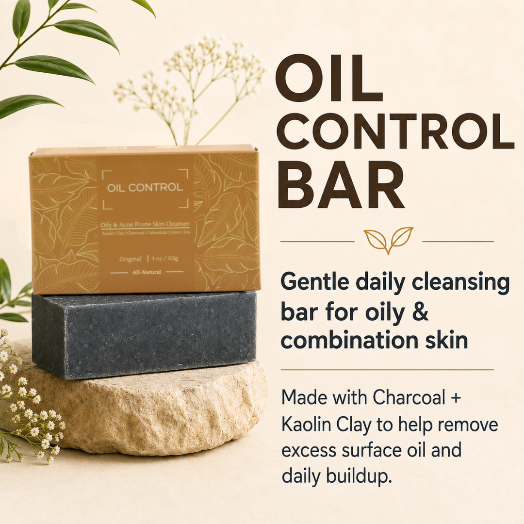 An oil control cleansing bar set shown on a beige background with decorative leaves and flowers. A tan branded box sits on top of a dark charcoal bar, which rests on a stone.